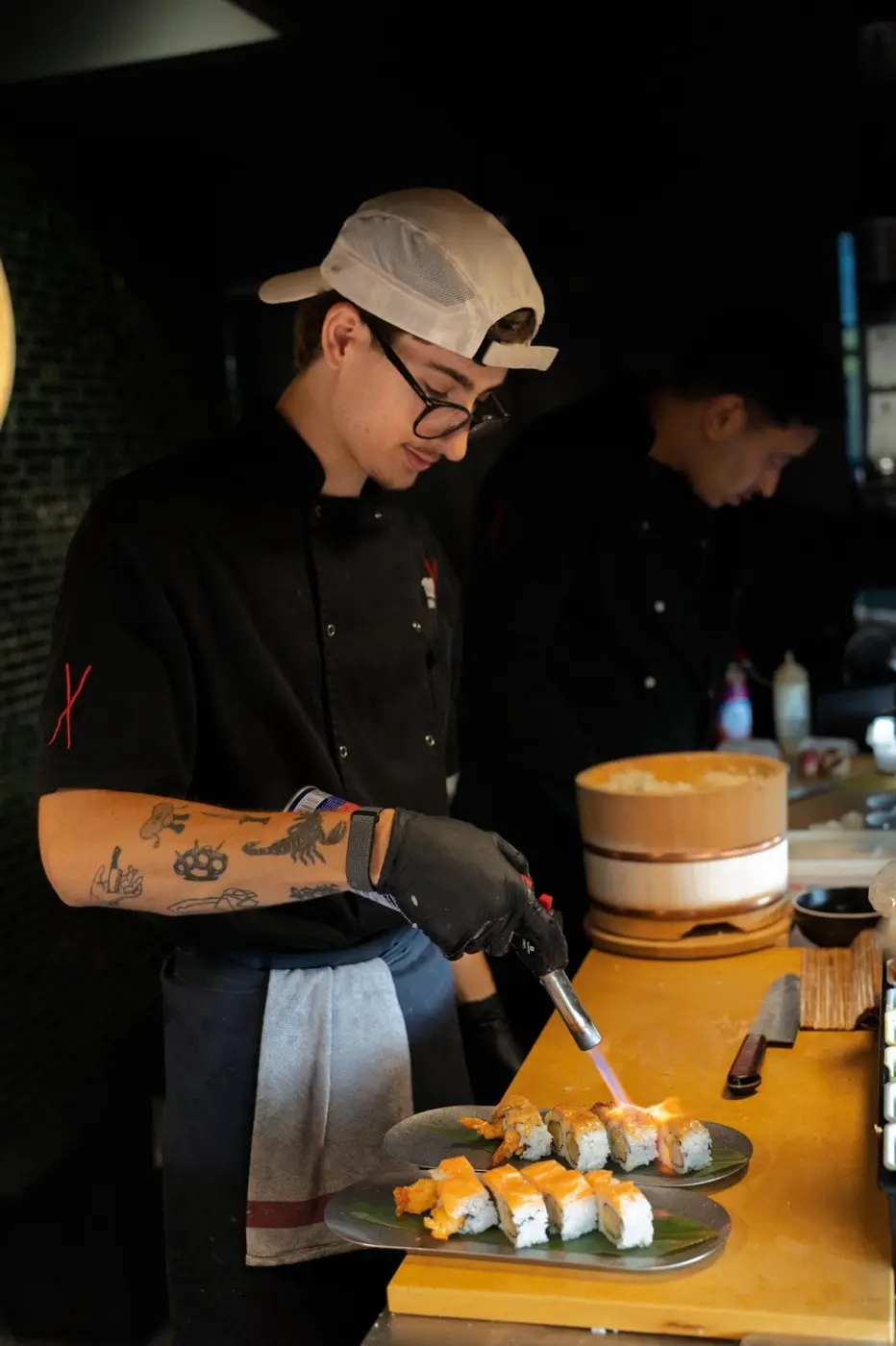 Sushiman de 220 Sushi flameando rolls de sushi con un soplete durante un catering