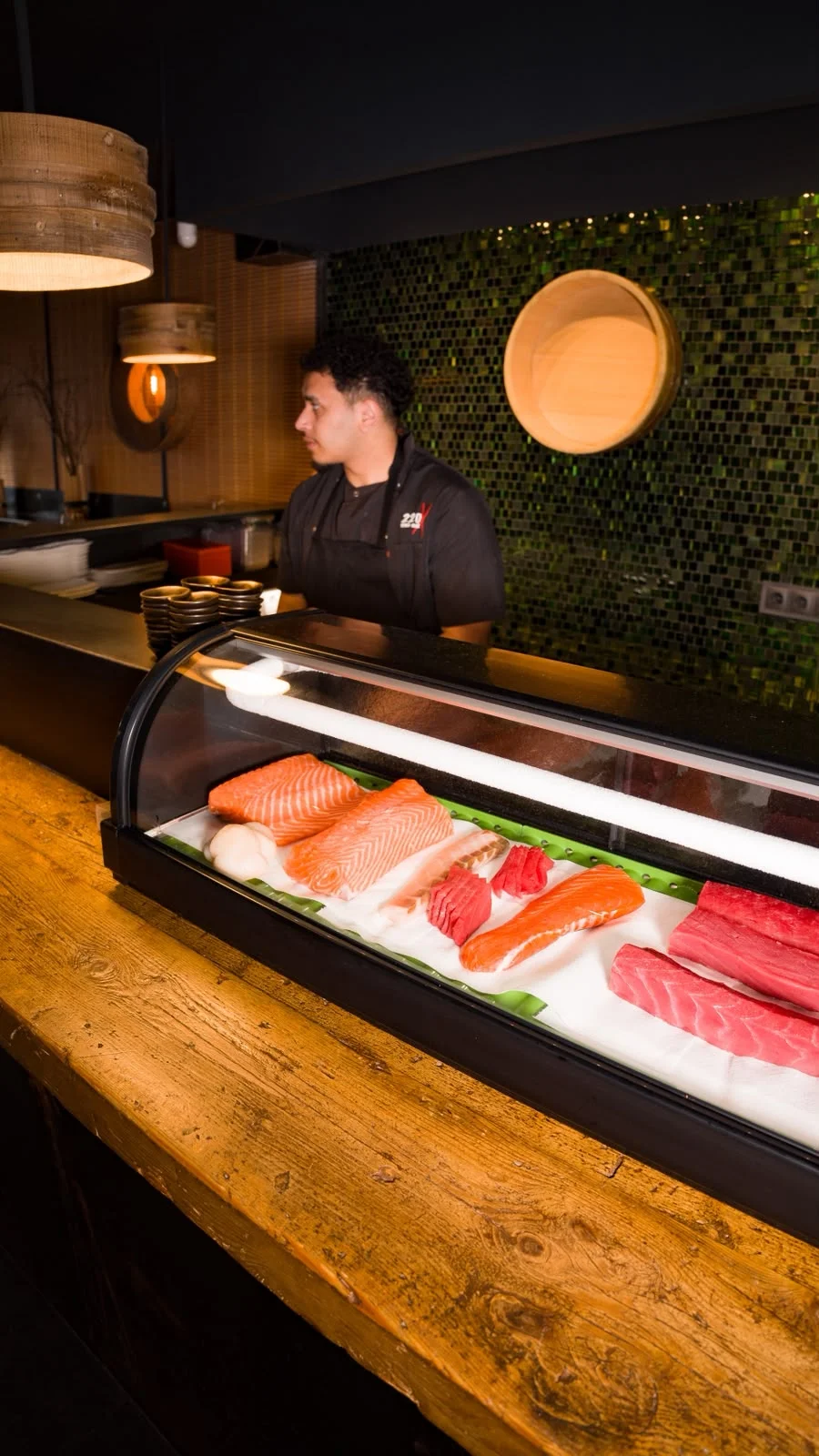 Chef de 220 Sushi junto a la vitrina de pescado fresco